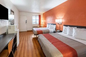 A hotel room with two beds, a desk, a television, and a window with curtains.