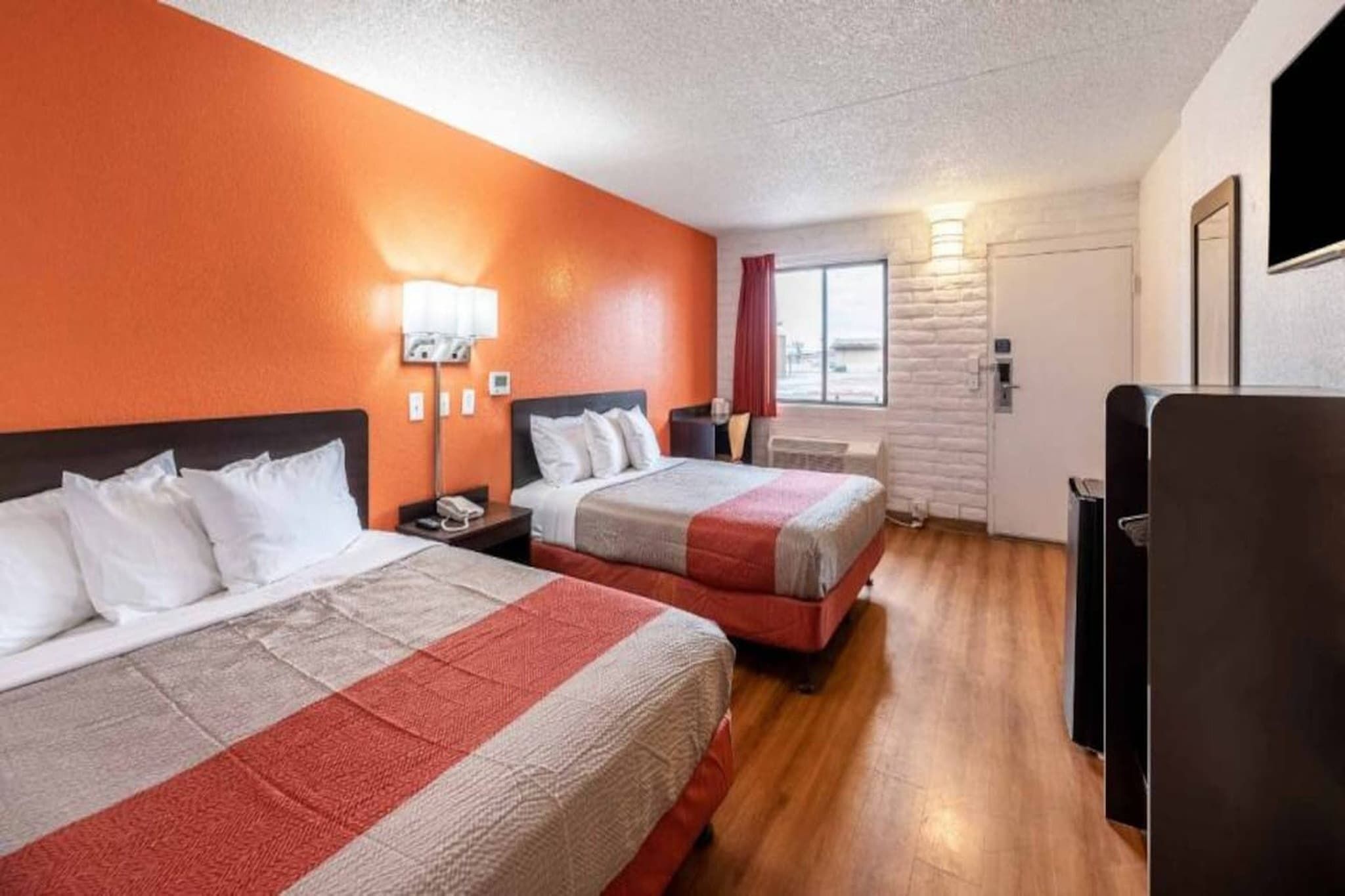 A hotel room with two beds, a large window, and a flat-screen TV.