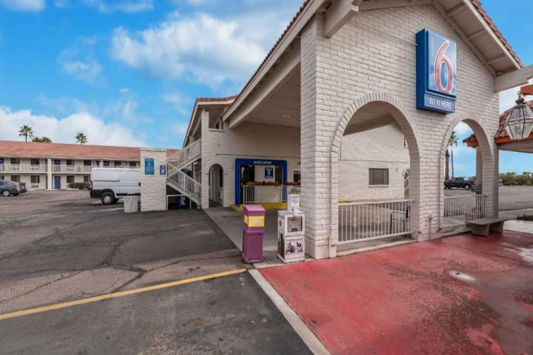 A motel with a '6' sign, a covered parking area, and a building with a red roof.