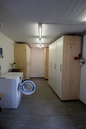A laundry room with a washing machine, drying rack, and wooden cabinets. - Porta Neff Appartement/Fewo, Bad, WC, 2 Schlafräume by Interhome (Bivio)