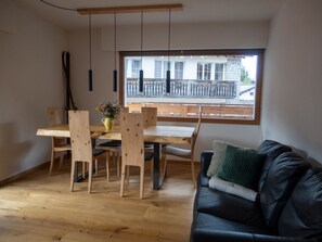A dining area with a wooden table and chairs, a vase with flowers, and a black leather couch with cushions. - Porta Neff Appartement/Fewo, Bad, WC, 2 Schlafräume by Interhome (Bivio)