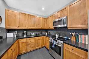A modern kitchen with wooden cabinets, a microwave, a kettle, and a coffee maker. - Mountain Views | Pool & Spa | Walk to Gondola | Village Dining | The Iron Horse (Truckee)