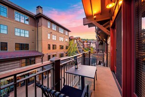 A balcony with a table, chairs, and a bottle of wine. - Mountain Views | Pool & Spa | Walk to Gondola | Village Dining | The Iron Horse (Truckee)