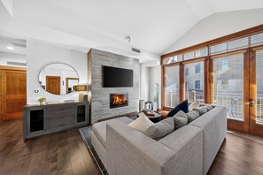 Ein modernes Wohnzimmer mit Kamin, einer großen Couch und einem an der Wand befestigten Fernseher.