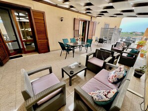 A spacious outdoor seating area with a glass table, cushioned chairs, and a sofa. - Vrbo Property (Marsala)