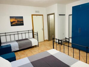A room with a bed, a blue wardrobe, a door, and a painting on the wall. - Vrbo Property (Marsala)
