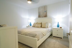 Ein Schlafzimmer mit Bett, Nachttischen, einer Kommode und einem Bild an der Wand.