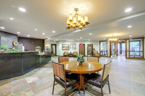 A hotel lobby with a reception desk, a round dining table with chairs, and a chandelier. - Gondola to Skiing! Steamboat Condo w/ Hot Tubs (Steamboat Springs)