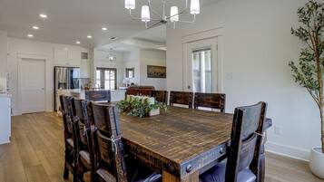 A dining area with a wooden table and chairs, a chandelier, and a potted plant.