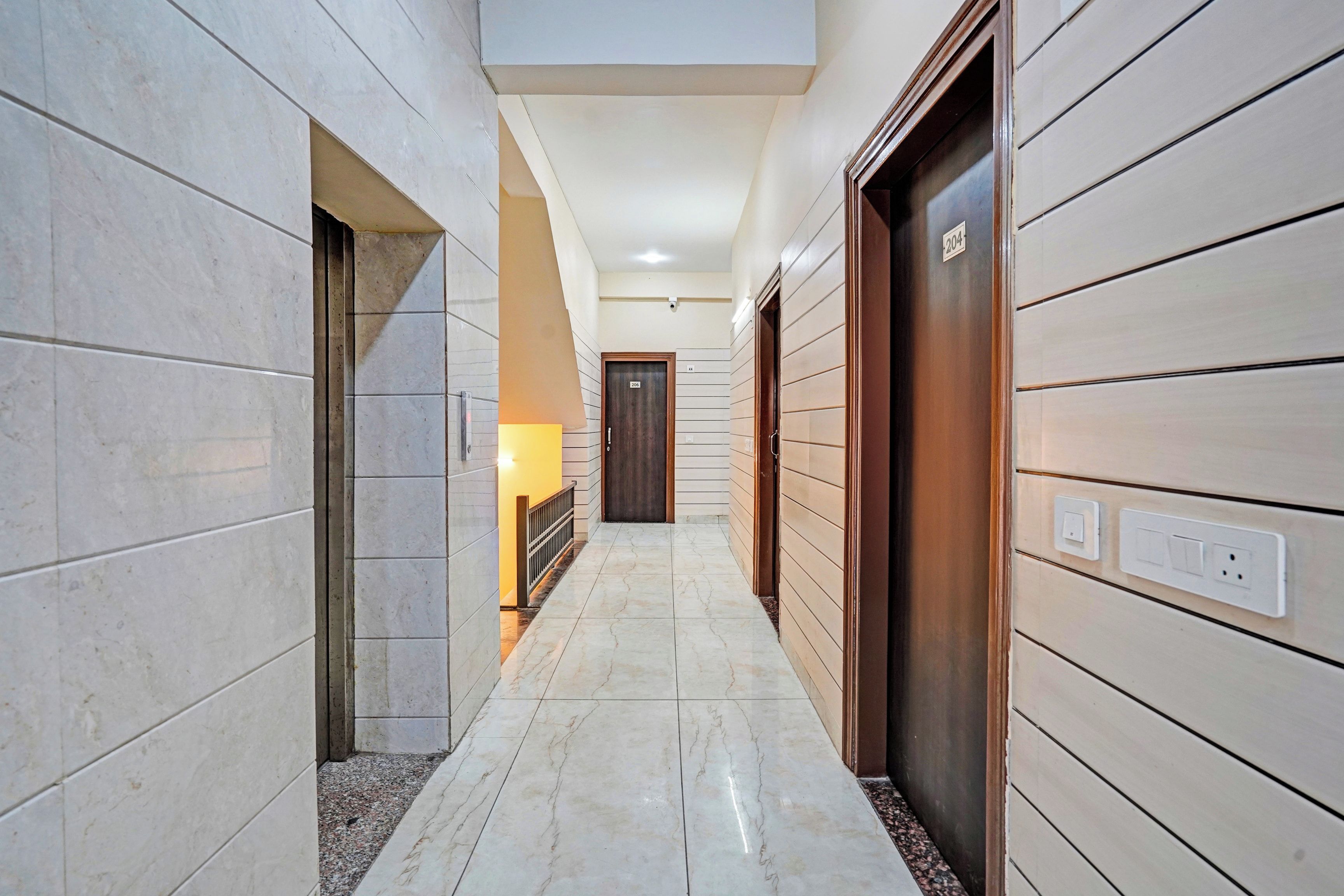 A hallway with a marble floor, wooden doors, and a light fixture.
