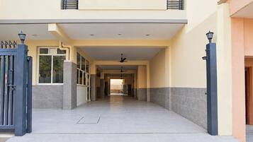 A building entrance with a gated driveway, a covered walkway, and a ceiling fan.