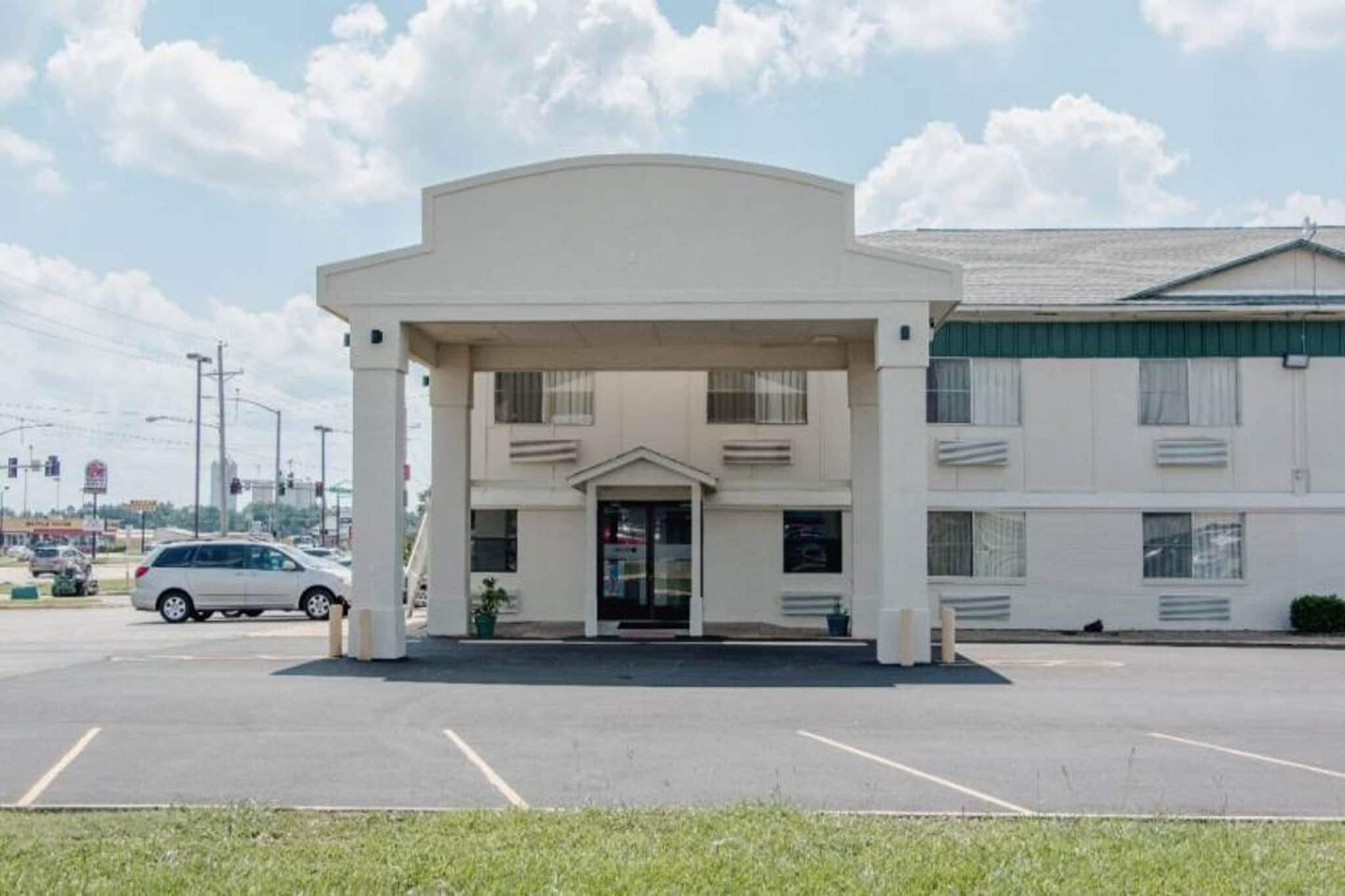 A building with a central entrance, a parking lot, and a vehicle in the foreground.