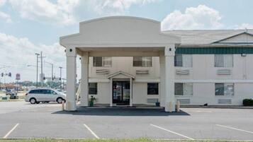 A building with a central entrance, a parking lot, and a vehicle in the foreground.