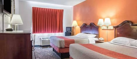 Une chambre d’hôtel avec deux lits, un bureau, une chaise, une télévision et une fenêtre avec des rideaux.