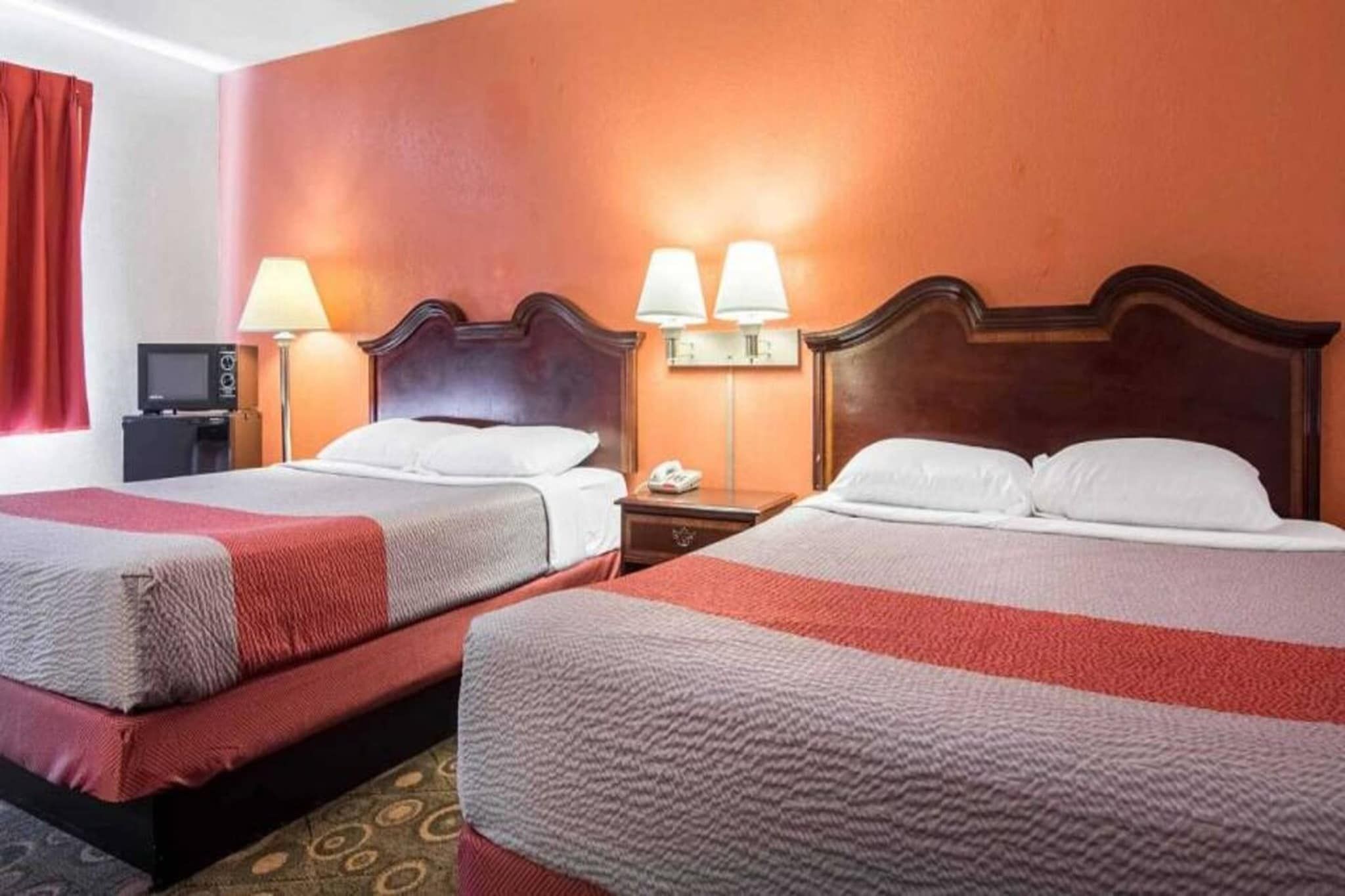 Een hotelkamer met twee bedden, een televisie en twee bedlampjes.