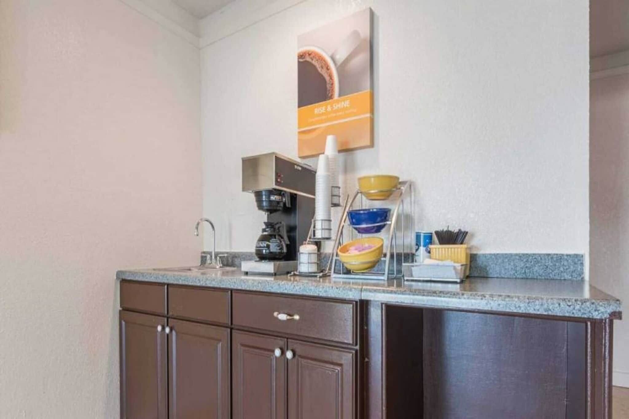 A kitchenette with a coffee maker, bowls, and a coffee station.