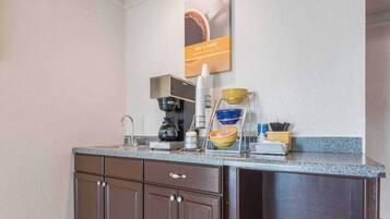 A kitchenette with a coffee maker, bowls, and a coffee station.