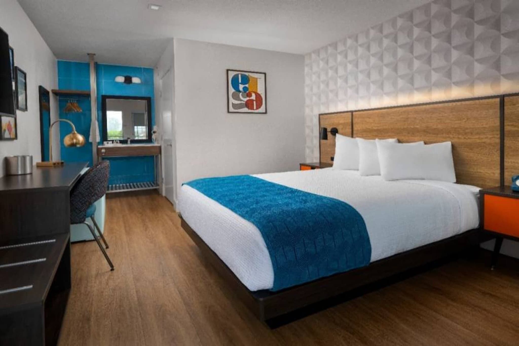 A hotel room with a large bed, a desk, a chair, and a bathroom.