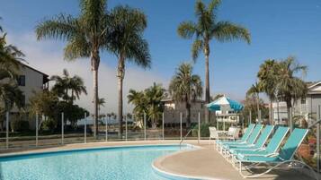 A swimming pool with lounge chairs and palm trees.