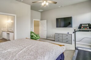 A bedroom with a bed, a television, a treadmill, and a bathroom with a sink and mirror. - Play & Unwind! Home w/ Fenced Yard in Amarillo (Amarillo)