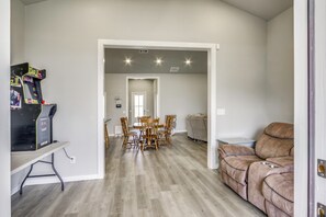 A spacious living area with a dining table and chairs, a couch, and a gaming console. - Play & Unwind! Home w/ Fenced Yard in Amarillo (Amarillo)