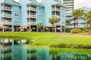 A multi-story hotel with balconies, a grassy area, and a body of water. - Unwind Poolside, Walk to Beach! Pensacola Getaway (Pensacola)