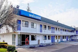 A motel with a 'Welcome' sign, numbered rooms, and a parking lot.