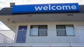 Un bâtiment avec une enseigne bleue portant l’inscription « Bienvenue » au-dessus d’une porte marquée du numéro « 201 ».
