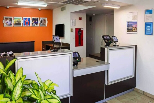 A reception area with two counters, a fire alarm, and a wall with framed pictures.