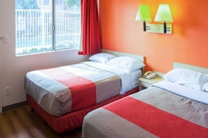 A hotel room with two beds, a window with a view, and a bedside telephone.