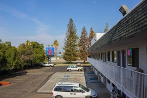 A motel with a parking lot, a building with a balcony, and a sign indicating the number 6.
