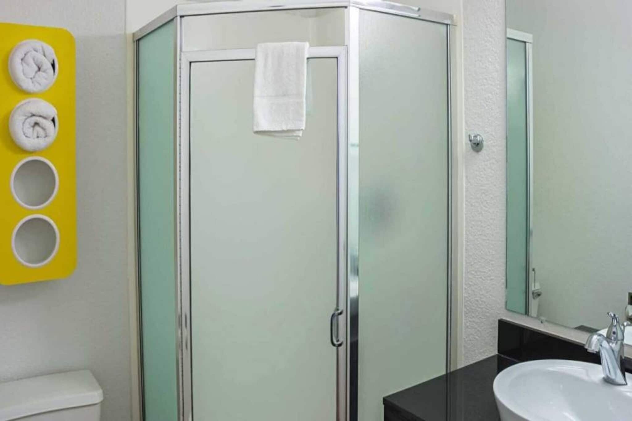 A bathroom with a glass-enclosed shower, a white sink, and a mirror.
