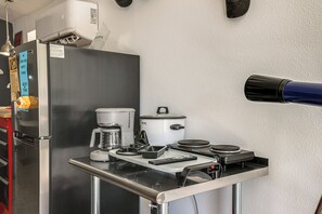 Cozinha equipada com geladeira, cafeteira e micro-ondas na bancada.