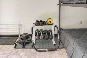 Espaço para ginástica em casa com um banco de musculação, suporte para halteres e barra.