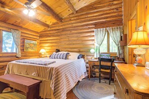 Ein Zimmer in einer Blockhütte mit Bett, Schreibtisch, Stuhl und Lampe.