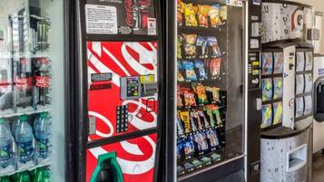 Una máquina expendedora con publicidad de Coca-Cola Zero, variedad de aperitivos y un dispensador de agua.