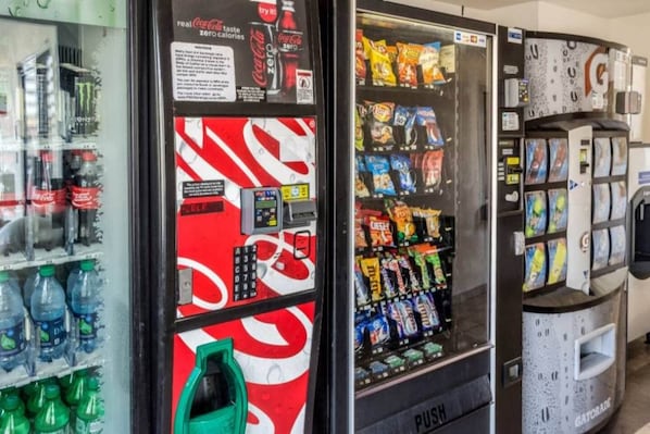 Un distributeur automatique affichant une publicité pour Coca-Cola Zero, proposant un assortiment de collations et muni d’un distributeur d’eau.