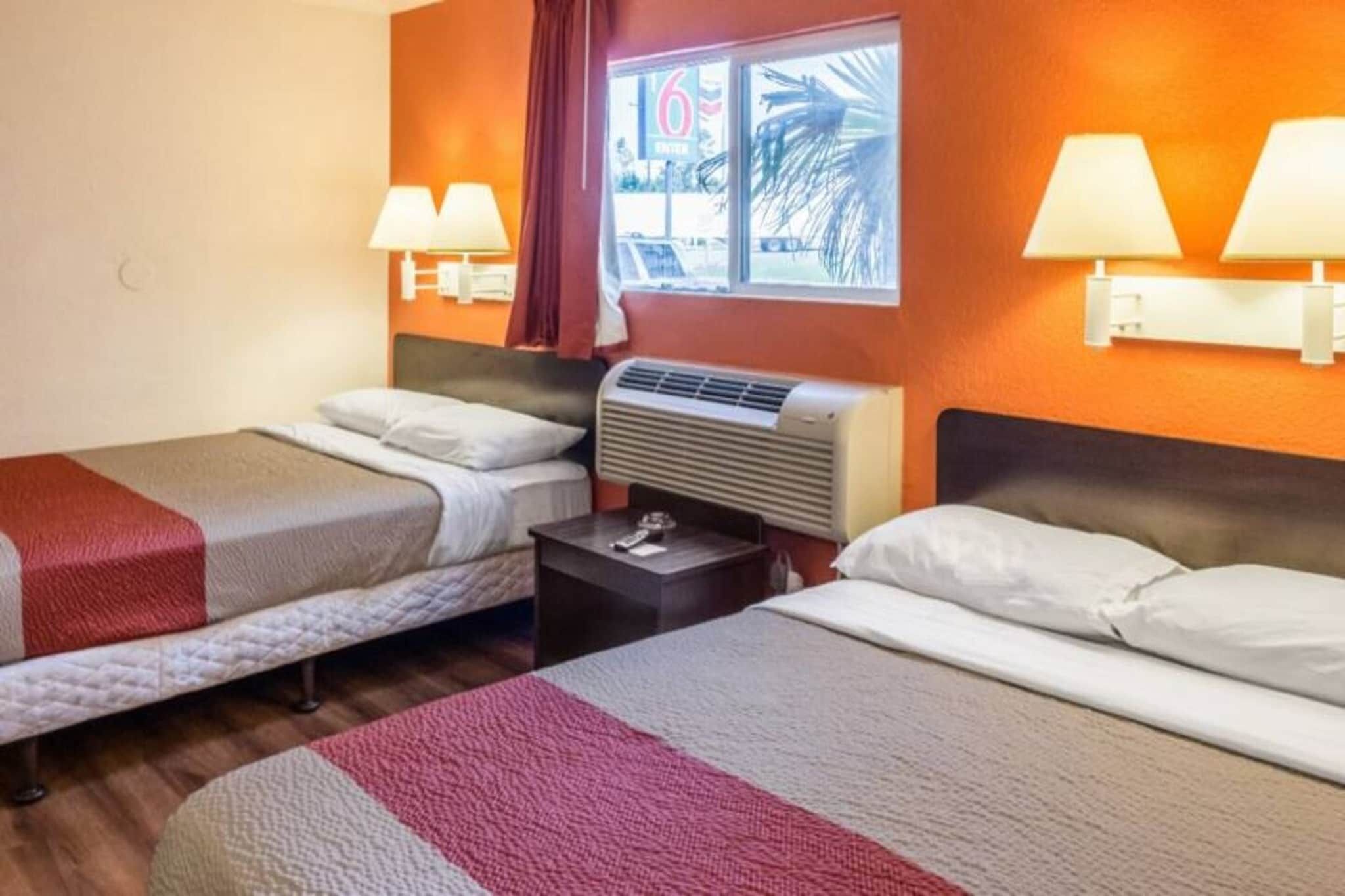 Habitación de hotel con dos camas, una mesita de noche, un ventanal con vistas y dos lámparas de pared.