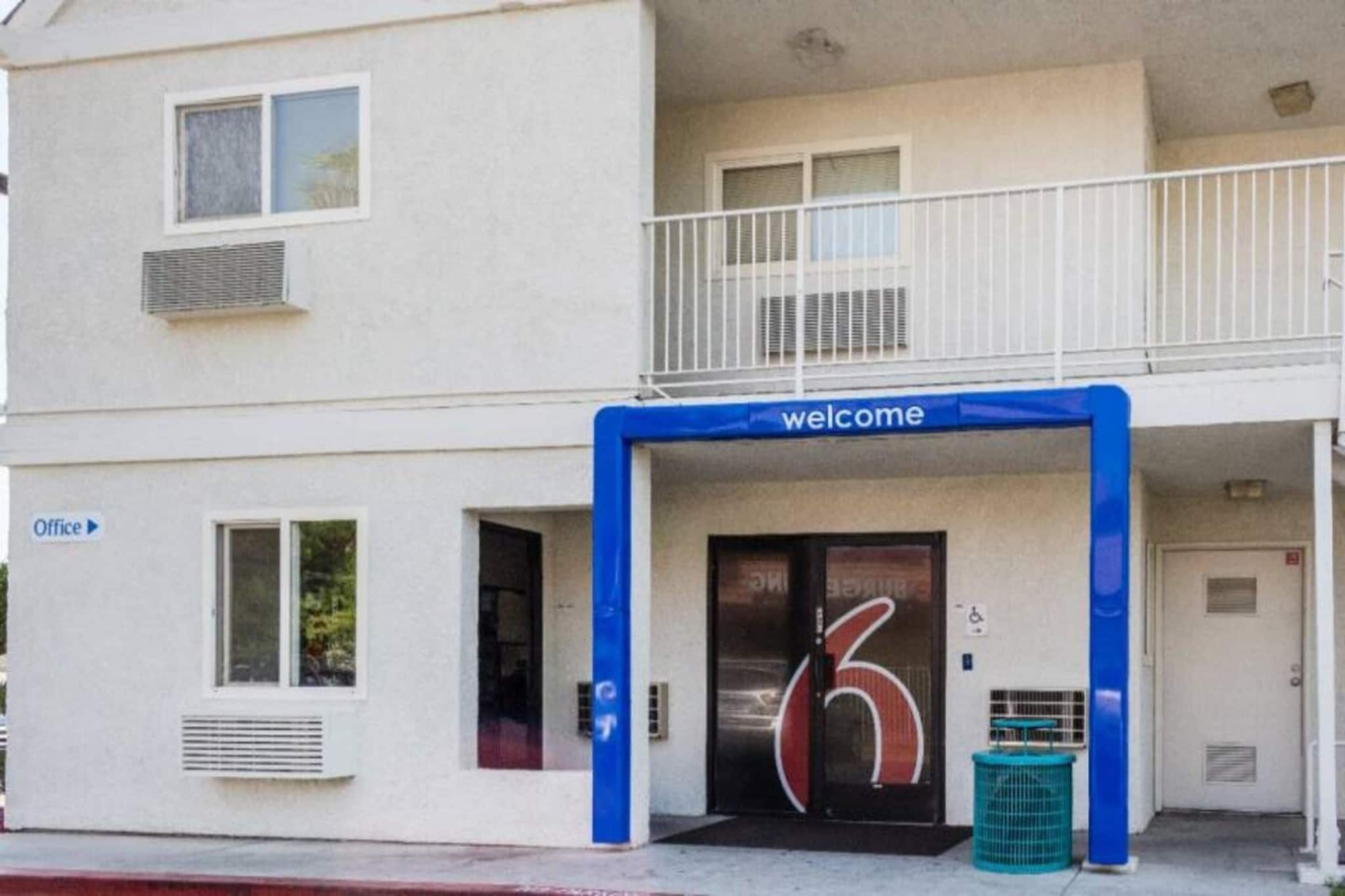 Ein Gebäude mit einem 'Welcome'-Schild über dem Eingang, einem sichtbaren Büroschild und einer Mülltonne davor.