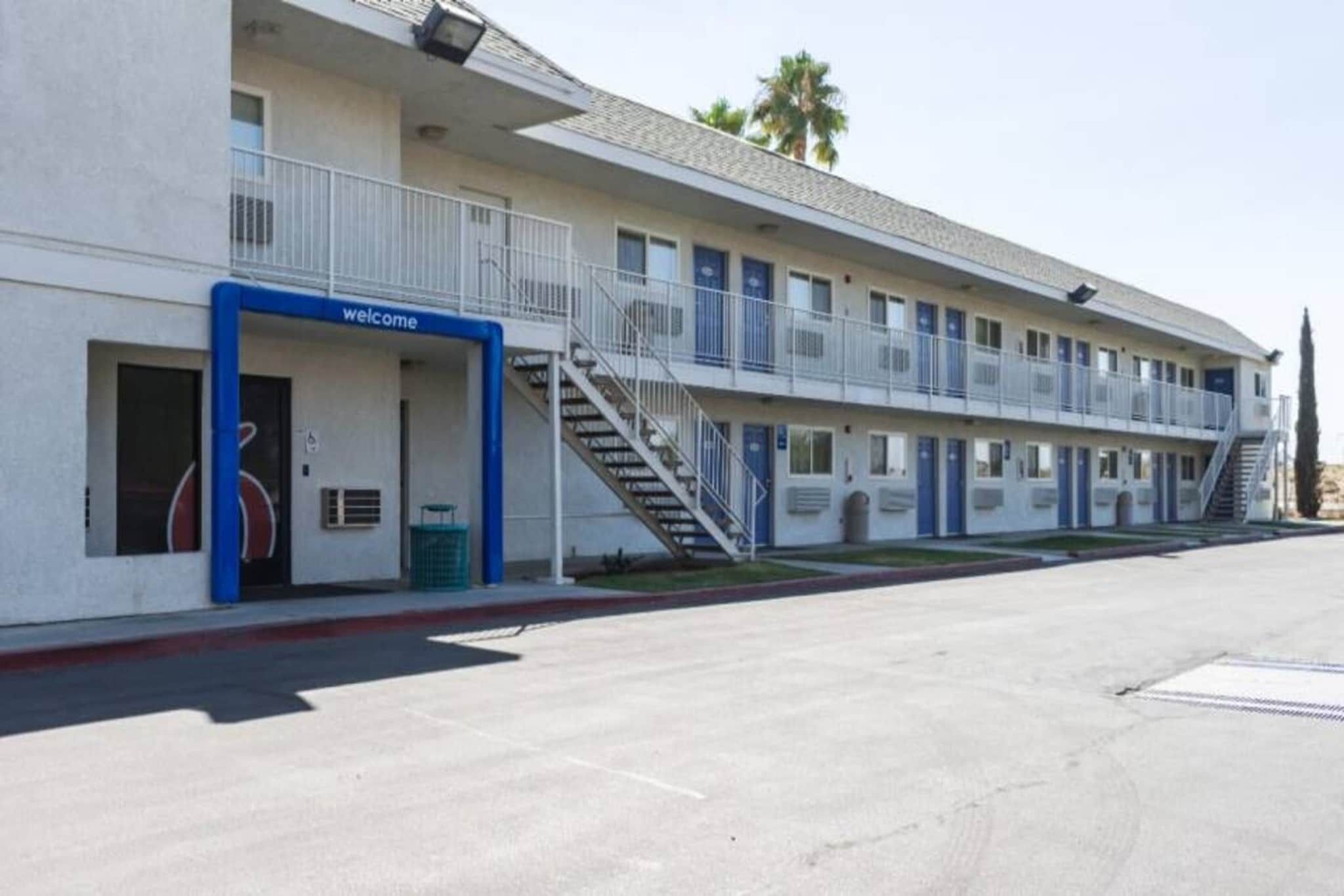 A motel with a 'welcome' sign, a covered outdoor area, and a parking lot.