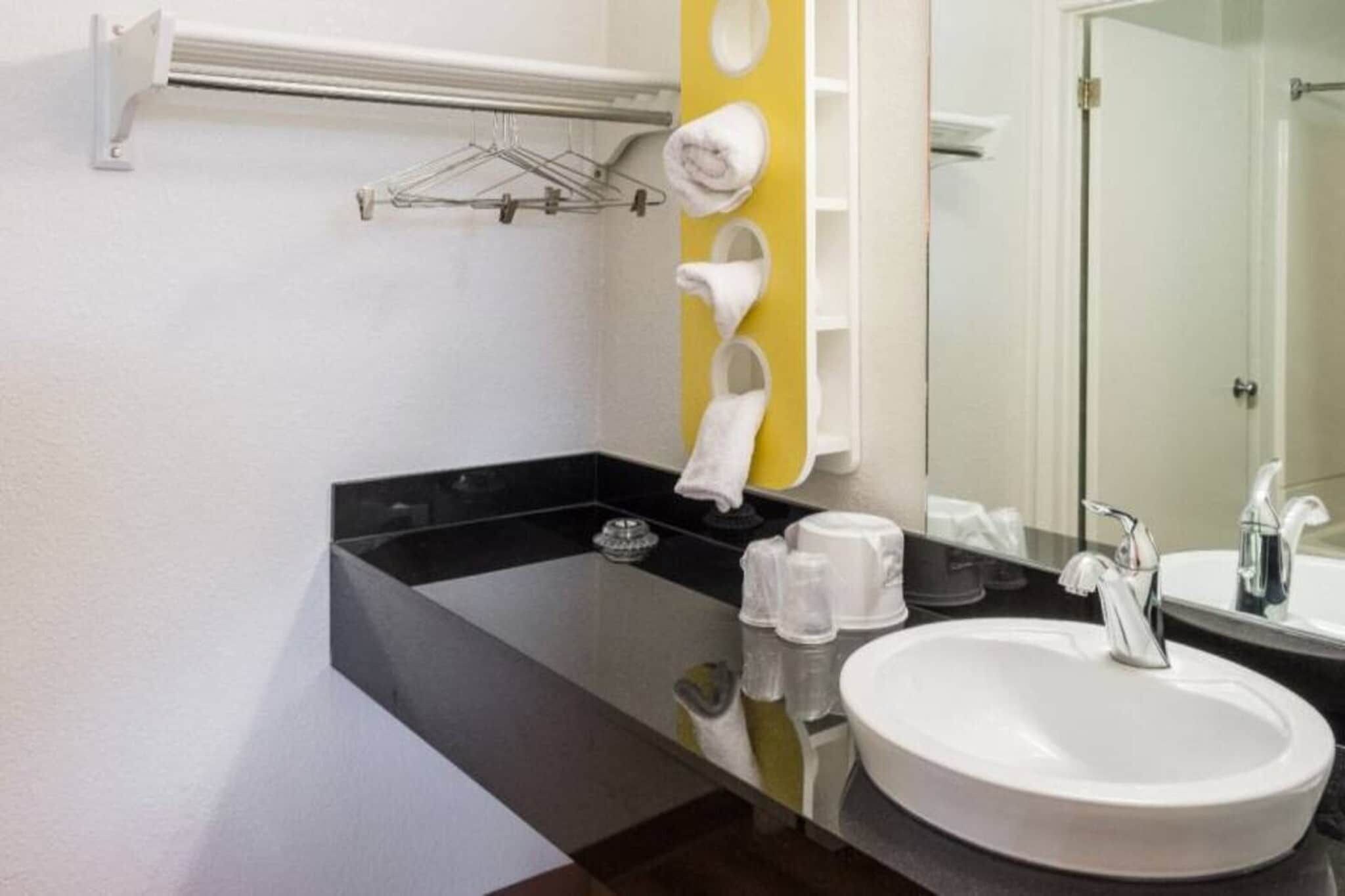A modern bathroom with a black countertop, a white sink, and a mirror.