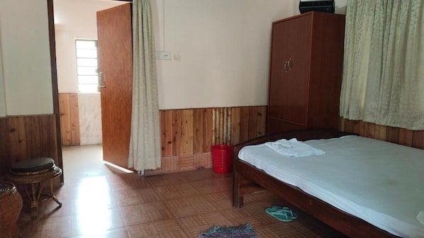 Une pièce comprenant un lit, une armoire, une petite table et une porte donnant sur une autre pièce.