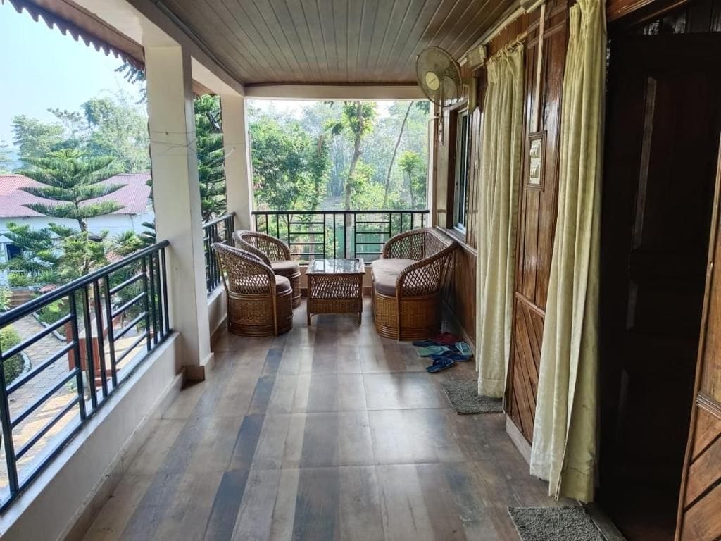 A balcony with wicker furniture, a fan, and a view of the surrounding greenery.