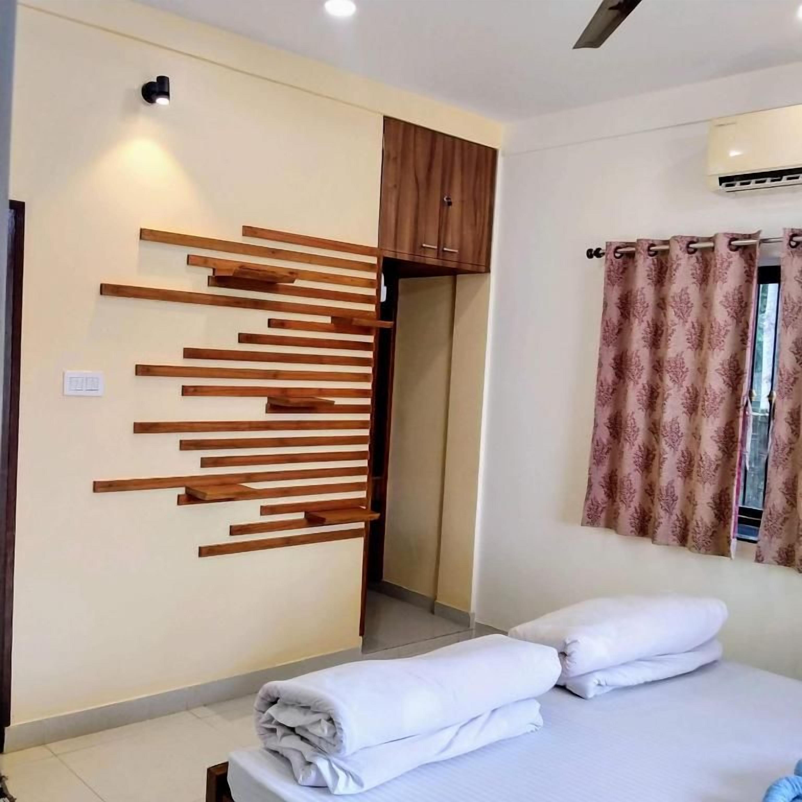 Habitación de hotel con cama, panel de madera en la pared, ventana con cortinas y equipo de aire acondicionado.