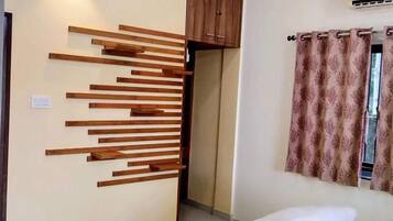 Habitación de hotel con cama, panel de madera en la pared, ventana con cortinas y equipo de aire acondicionado.