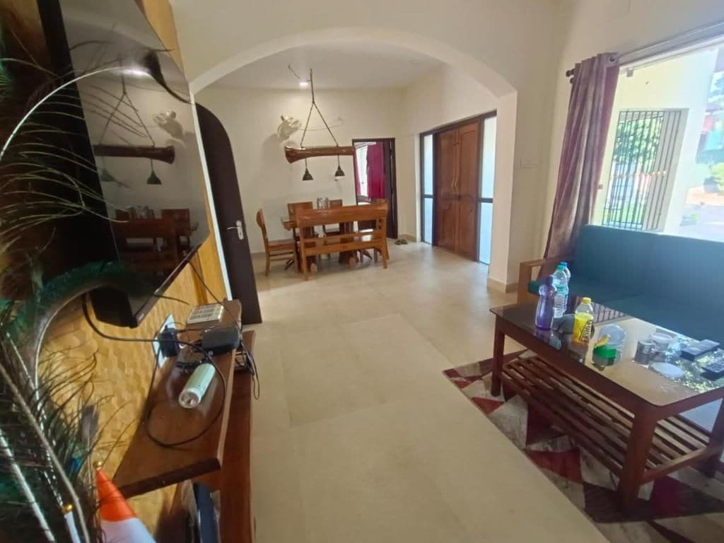 A spacious living area with a dining table, a sofa, and a TV.
