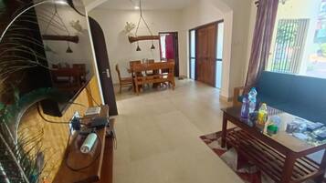A spacious living area with a dining table, a sofa, and a TV.