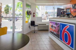 Interior d'un motel amb una finestra gran, una cadira, una taula i un cartell publicitant l'allotjament.