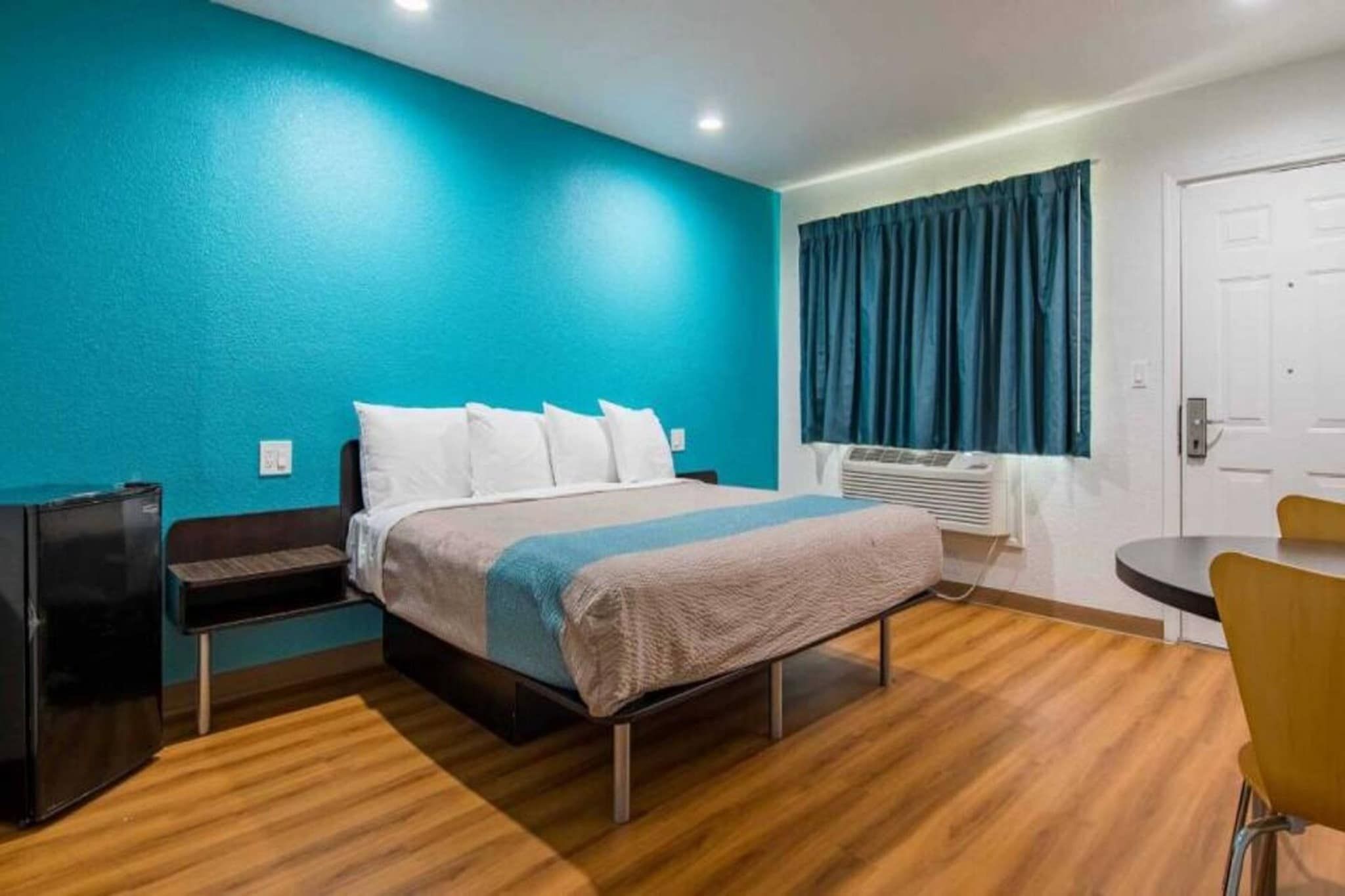 Une chambre d’hôtel avec un lit, un bureau, une chaise et une fenêtre avec des rideaux.