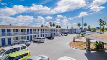 A motel with multiple rooms, a parking lot, and a clear sky.